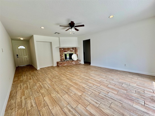unfurnished living room with ceiling fan, wood tiled floors, baseboards, recessed lighting, and a brick fireplace