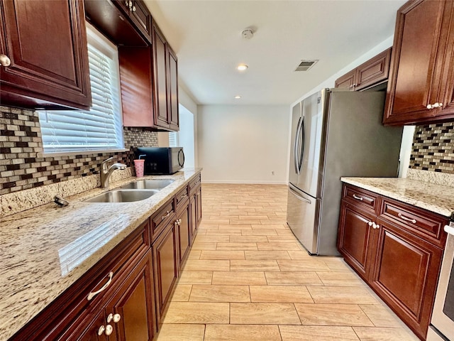 kitchen with black microwave, a sink, decorative backsplash, baseboards, and recessed lighting