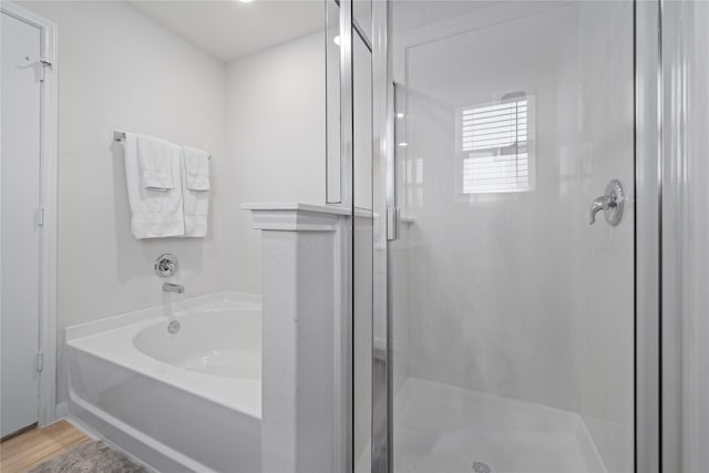 bathroom with a stall shower, a bath, and wood finished floors