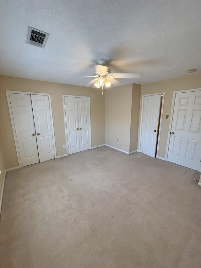 20003 Powerscourt Dr, Humble, TX 77346 - unfurnished bedroom with two closets, baseboards, light carpet, and ceiling fan