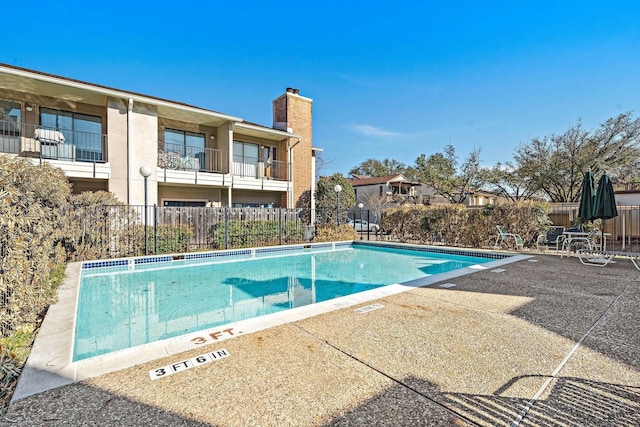 community pool with fence and a patio area
