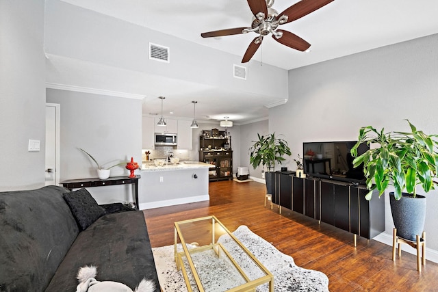 living area with ceiling fan, dark wood-type flooring, and baseboards