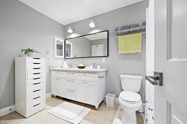 bathroom featuring baseboards, toilet, double vanity, and tile patterned flooring