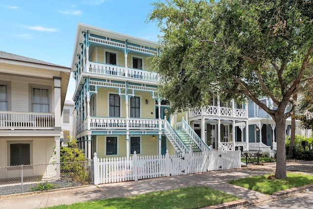 view of front facade featuring a porch, a balcony, a fenced front yard, and stairway