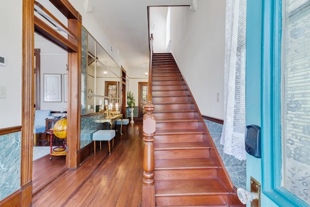stairs with wood-type flooring and ornamental molding