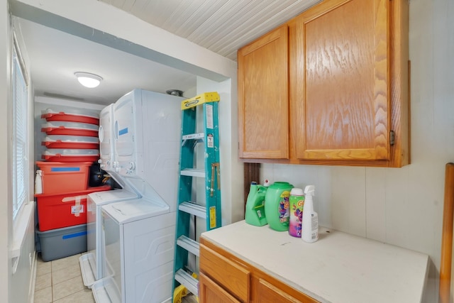laundry room featuring stacked washer and clothes dryer, cabinet space, and light tile patterned flooring