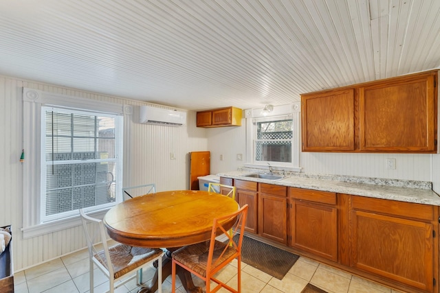 kitchen with a sink, light tile patterned floors, healthy amount of natural light, a wall unit AC, and wooden walls