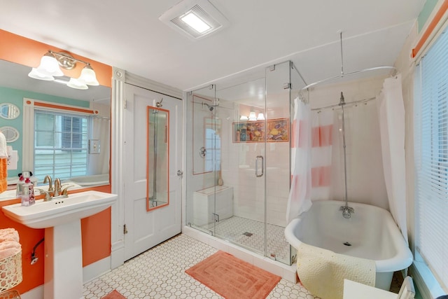 full bathroom featuring a stall shower, a freestanding bath, tile patterned floors, and a sink