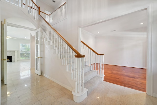 1706 Lofty Maple Trl, Houston, TX 77345 - staircase featuring baseboards, ceiling fan, a high ceiling, a high end fireplace, and ornamental molding