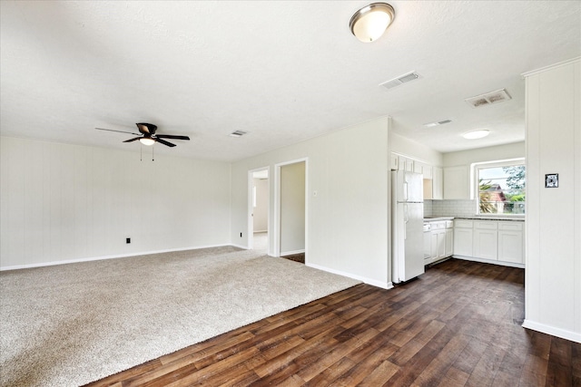 unfurnished living room with dark wood-style floors, a ceiling fan, and baseboards