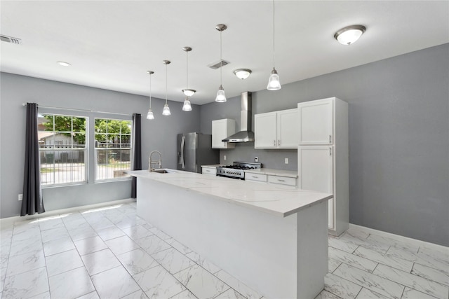 kitchen with wall chimney exhaust hood, stainless steel appliances, light marble finish floors, a sink, and white cabinets