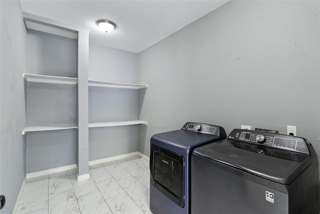 laundry area featuring independent washer and dryer, light marble finish flooring, and baseboards