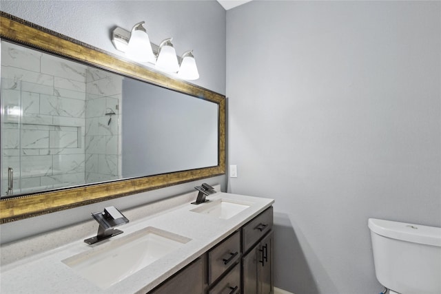 bathroom featuring toilet, a tile shower, and double vanity