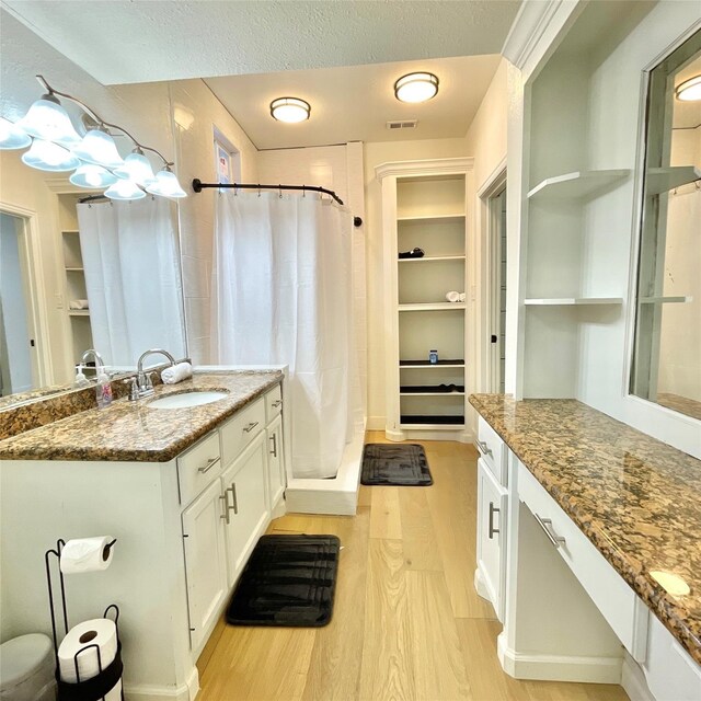 full bath with wood finished floors, built in features, a textured ceiling, vanity, and a shower with shower curtain