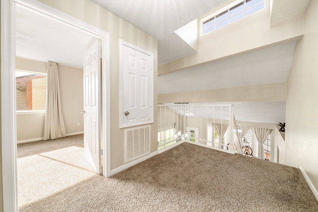 hall featuring carpet flooring, plenty of natural light, and baseboards