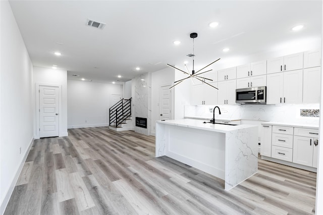 610 E 41st St Unit A B, Houston, TX 77022 - kitchen with stainless steel microwave, a sink, recessed lighting, light wood-type flooring, and white cabinets