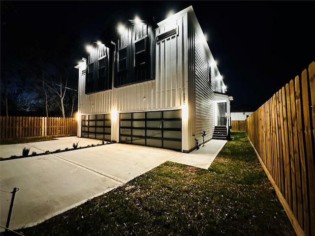 610 E 41st St Unit A B, Houston, TX 77022 - property exterior at twilight with a garage, fence, driveway, and board and batten siding