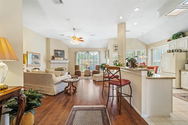 12938 Quail Park Dr, Cypress, TX 77429 - kitchen with freestanding refrigerator, vaulted ceiling, ceiling fan, a breakfast bar area, and a tiled fireplace