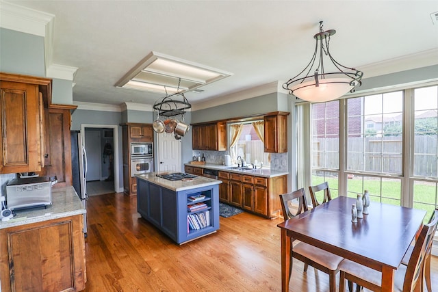 101 N Hall Dr, Sugar Land, TX 77478 - kitchen with stainless steel appliances, plenty of natural light, brown cabinetry, ornamental molding, and light wood finished floors