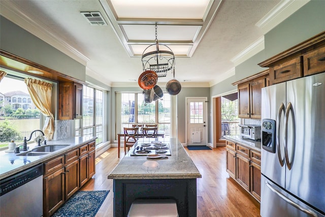 101 N Hall Dr, Sugar Land, TX 77478 - kitchen with appliances with stainless steel finishes, a sink, a kitchen island, light wood-style floors, and ornamental molding