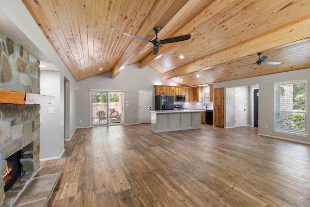 21 Riverbank Dr, The Woodlands, TX 77381 - kitchen featuring black fridge with ice dispenser, open floor plan, ceiling fan, stainless steel microwave, and a stone fireplace