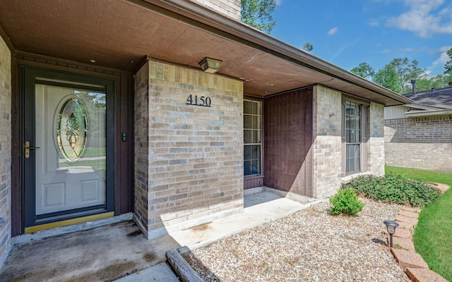 property entrance featuring brick siding, covered porch, and a chimney