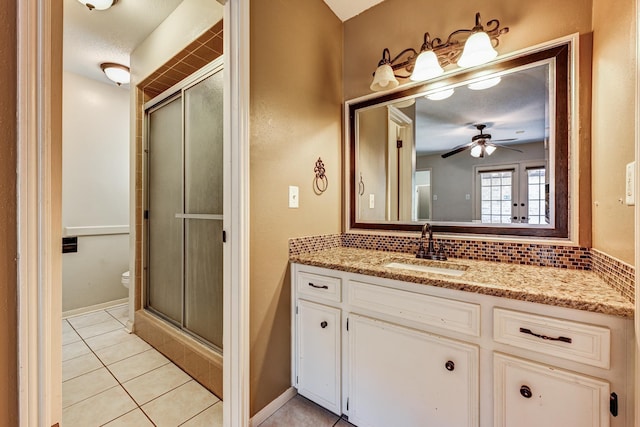 bathroom featuring a stall shower, vanity, tile patterned floors, a ceiling fan, and decorative backsplash