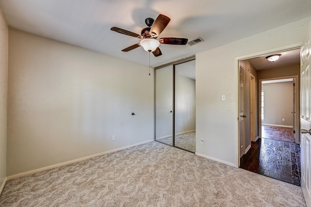 unfurnished bedroom with carpet floors, a closet, baseboards, and a ceiling fan