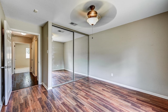 unfurnished bedroom featuring wood finished floors, baseboards, a closet, and ceiling fan