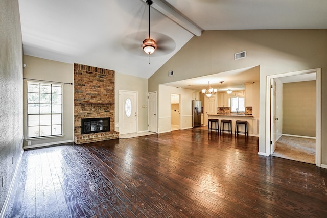 unfurnished living room with ceiling fan, high vaulted ceiling, a chandelier, wood-type flooring, and beamed ceiling