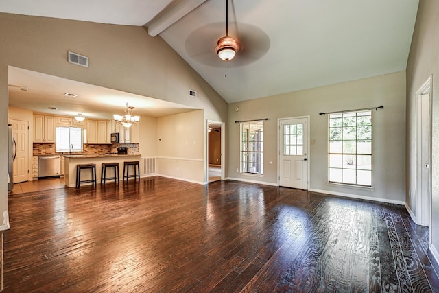 unfurnished living room featuring ceiling fan, a chandelier, wood-type flooring, beamed ceiling, and healthy amount of natural light