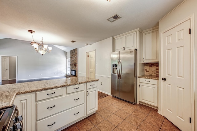 kitchen featuring appliances with stainless steel finishes, a chandelier, backsplash, light tile patterned floors, and vaulted ceiling