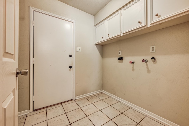 laundry room featuring cabinet space, baseboards, and light tile patterned floors
