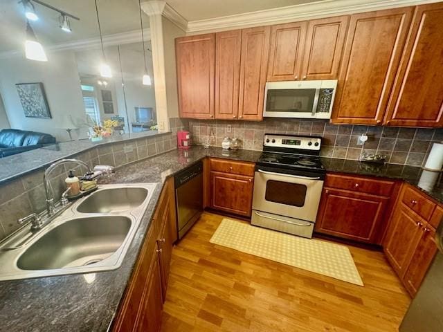 1711 Old Spanish Trl Unit 323, Houston, TX 77054 - kitchen with stainless steel appliances, a sink, light wood-style flooring, crown molding, and decorative backsplash