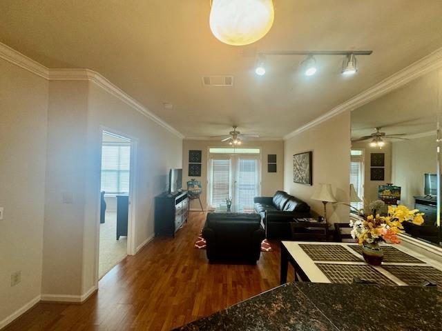 living room with a ceiling fan, wood finished floors, baseboards, and ornamental molding