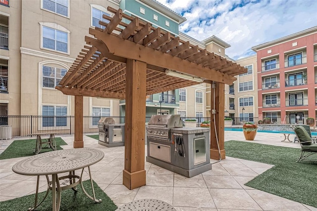 view of patio / terrace featuring a pergola, area for grilling, an outdoor kitchen, and a community pool