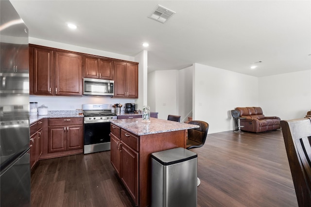 247 Pine Cavern Dr, Willis, TX 77378 - kitchen featuring appliances with stainless steel finishes, dark wood-style floors, light stone countertops, open floor plan, and a center island