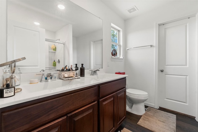 247 Pine Cavern Dr, Willis, TX 77378 - full bath with double vanity, toilet, wood finished floors, a shower with shower door, and recessed lighting