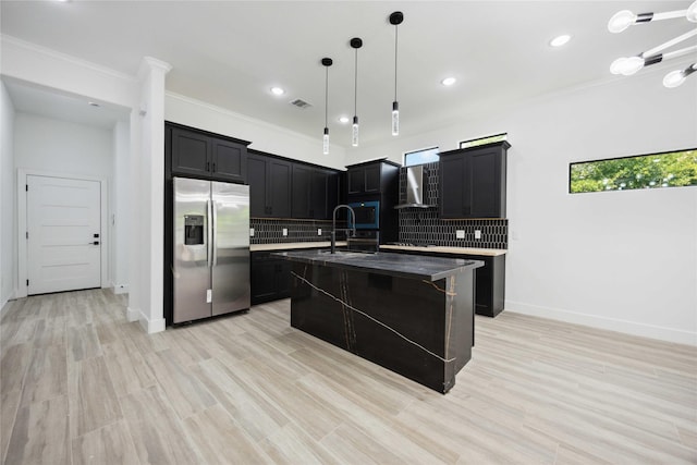 kitchen with stainless steel appliances, wall chimney exhaust hood, decorative backsplash, crown molding, and dark cabinets