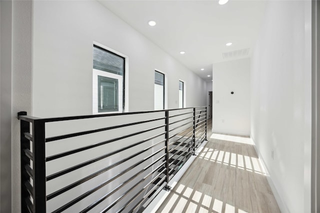 corridor featuring an upstairs landing, recessed lighting, wood finished floors, and baseboards