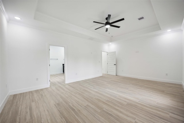 empty room featuring a tray ceiling, crown molding, a ceiling fan, light wood finished floors, and baseboards