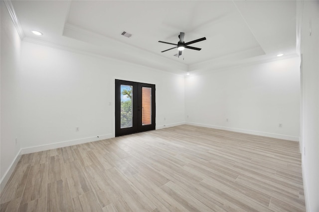 spare room featuring a raised ceiling, crown molding, french doors, light wood finished floors, and recessed lighting