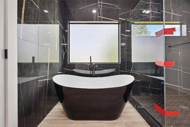 bathroom with tile walls, a freestanding bath, and walk in shower