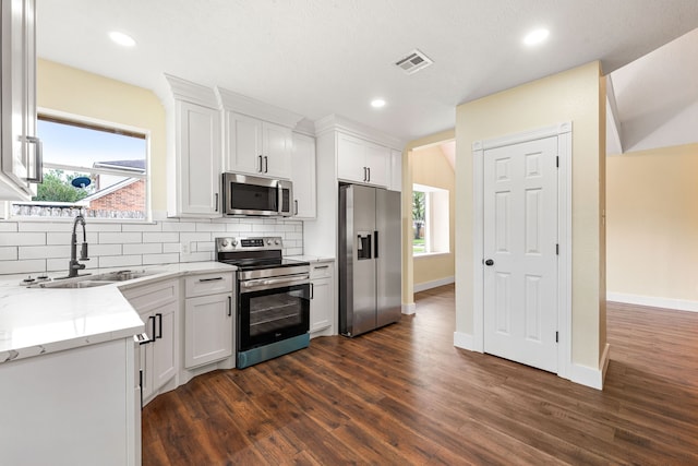 1408 Quail Holw, Sealy, TX 77474 - kitchen featuring stainless steel appliances, a sink, tasteful backsplash, dark wood-style floors, and white cabinetry