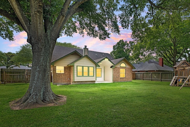 1408 Quail Holw, Sealy, TX 77474 - back of house at dusk with a playground, brick siding, and a chimney