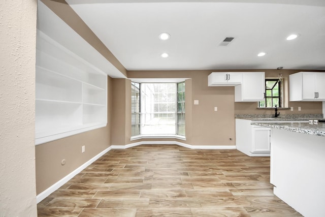 2257 County Road 206, Alvin, TX 77511 - kitchen featuring recessed lighting, white cabinetry, light stone counters, baseboards, and light wood-style floors