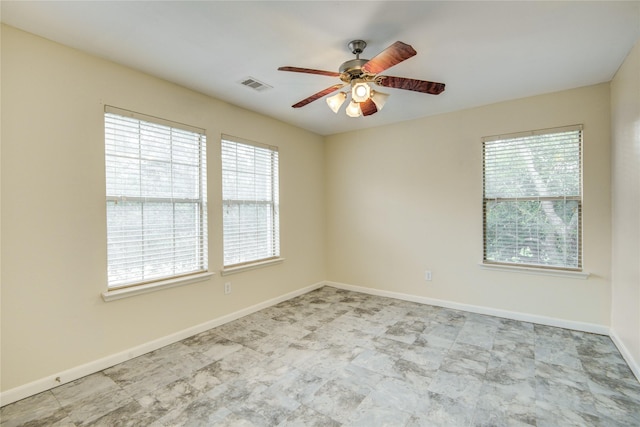 spare room with a ceiling fan, healthy amount of natural light, and baseboards