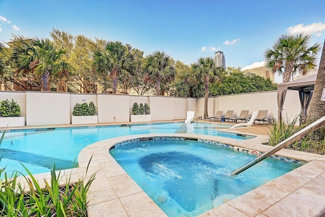 view of pool featuring an in-ground hot tub and fence