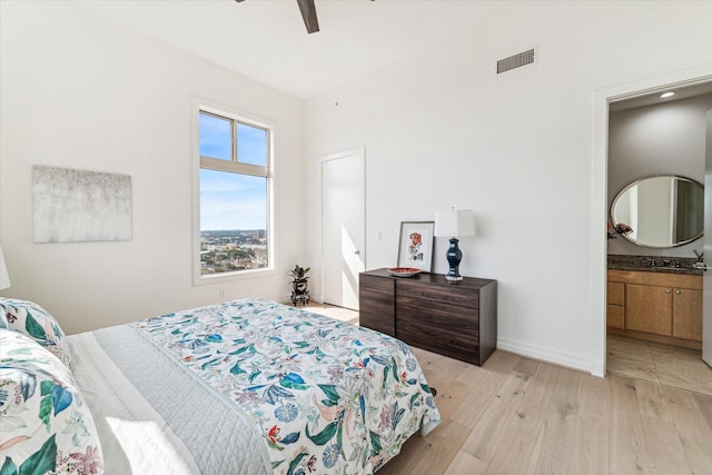 bedroom featuring light wood-type flooring, baseboards, ceiling fan, and ensuite bathroom