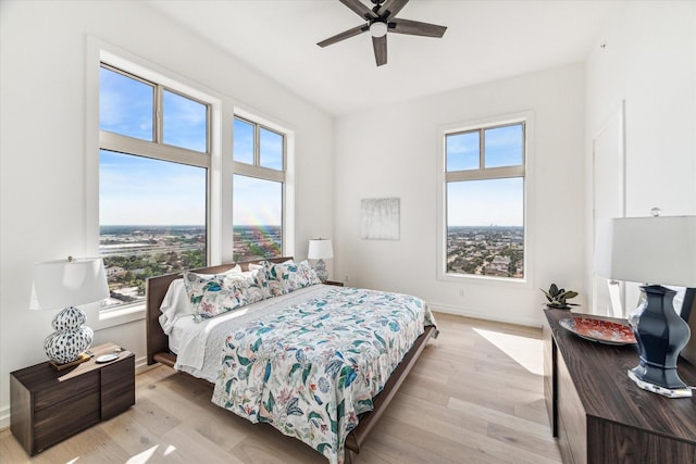 bedroom with multiple windows, light wood-type flooring, and baseboards